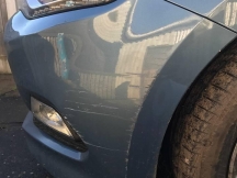 Close up of blue metallic car front bumper with scratches