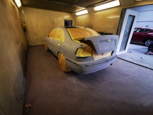 Car in spray booth prepared with paper and tape for a respray