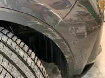 Close up of grey metallic car with scratch damage to front wheel arch