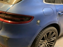 Dusty blue car with sanded areas during repair process