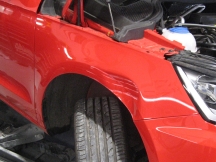 Red car with scratch and dent to front wheel arch