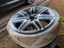Alloy wheel prepped with protective paper for paintwork repair on a driveway