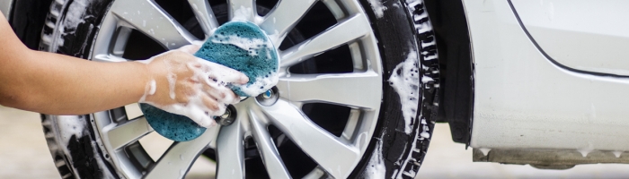 cleaning the cars alloy wheels with a blue cloth and soap.