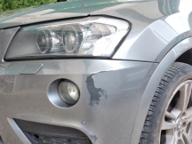 Grey car paintwork damage to passenger side from bumper and headlight