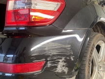 Black car with lots of scratches on rear bumper