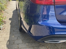 Blue car with repair to left side of rear bumper