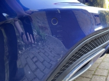Blue car with scratch to left side of rear bumper close up
