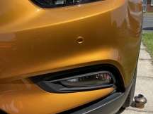 Orange car with repair to front bumper in sun