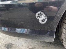 Dusty black car with scratch near rear wheel arch